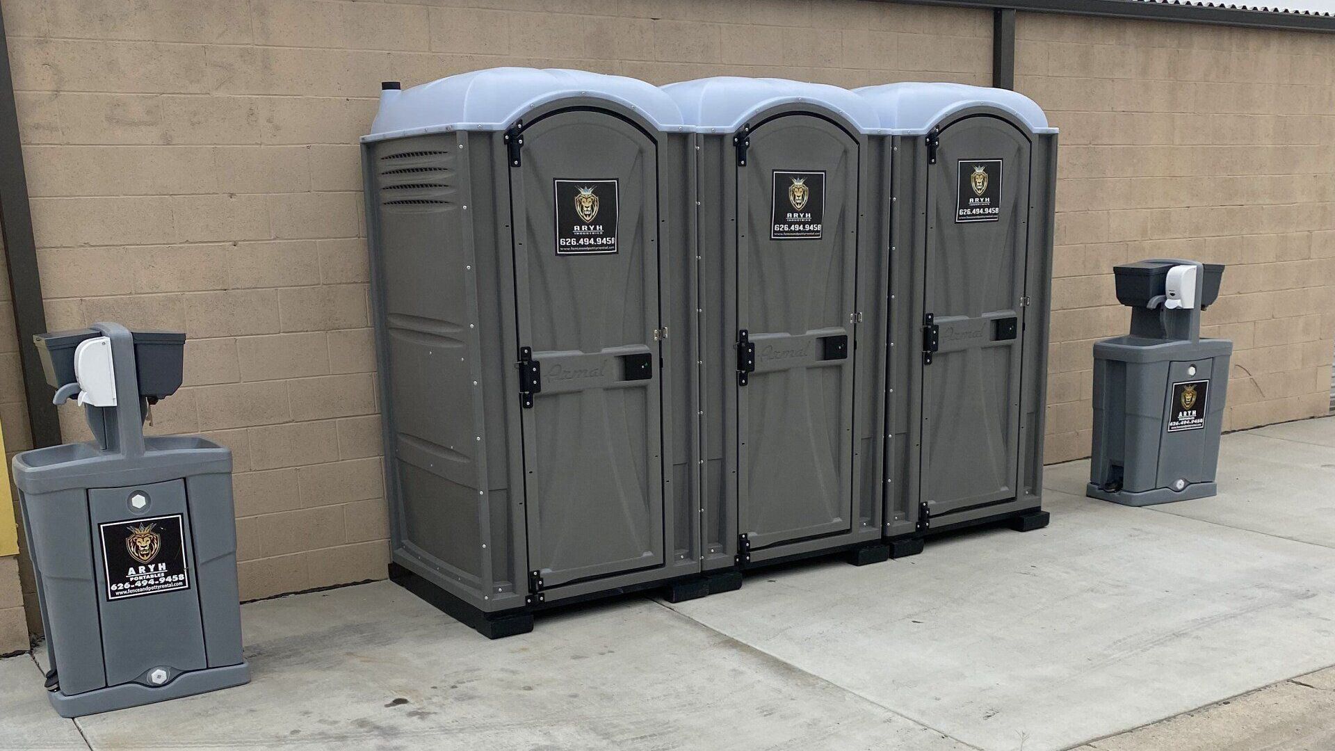 A row of portable toilets sitting next to each other on a sidewalk.