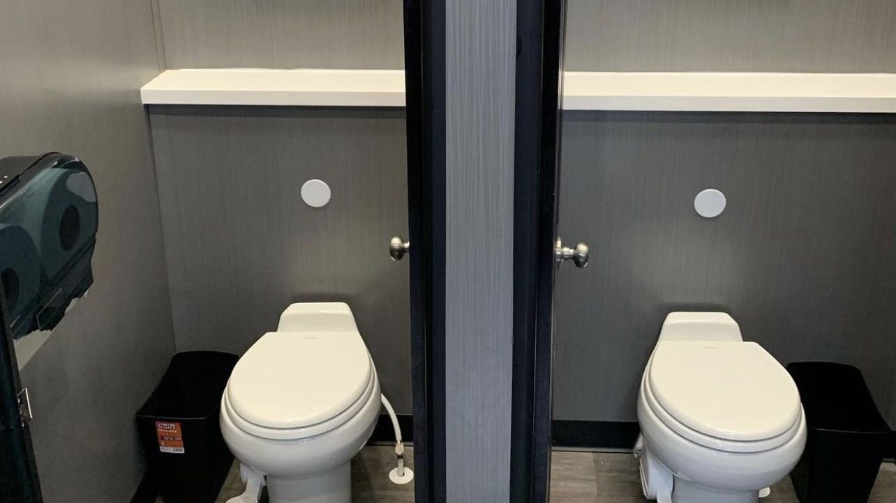 Two clean toilets are sitting next to each other.