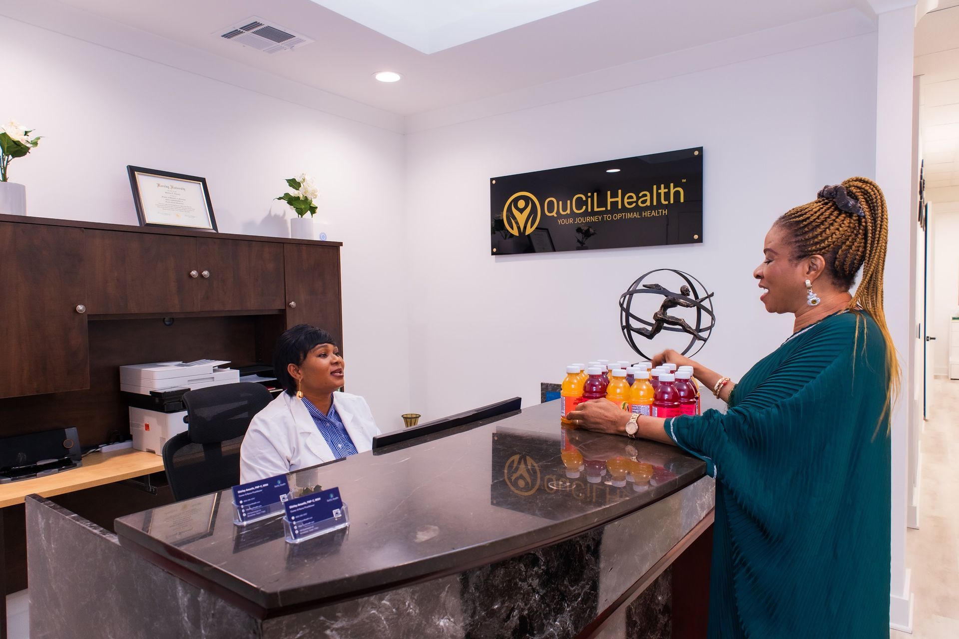 A woman is standing at a counter in a hospital talking to a doctor.