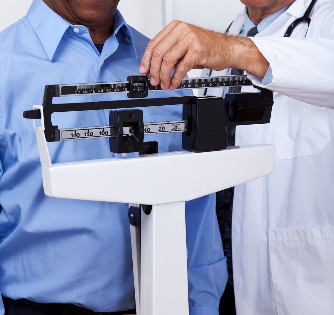 A man is being weighed on a scale by a doctor