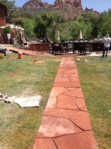 Red flagstone pathway leading to a dining area with a mountain backdrop.