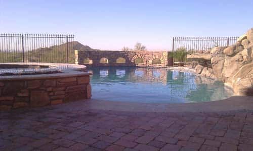 Pool area with pool, hot tub, stone details, and mountain view.