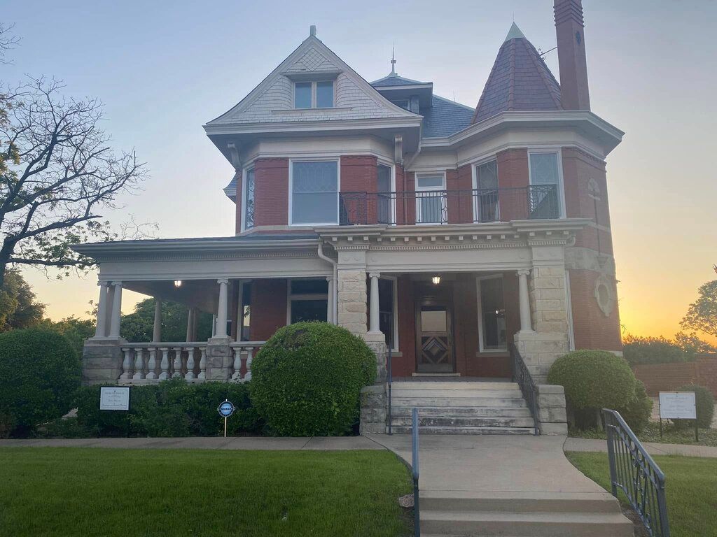 A large brick house with a large porch and stairs