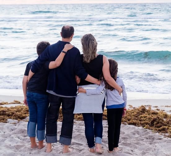 A family standing on a beach looking at the ocean