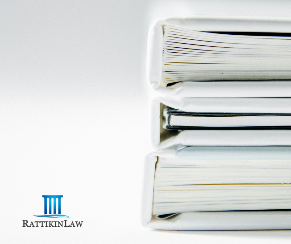 Stack of notebooks with legal documents and RattikinLaw logo