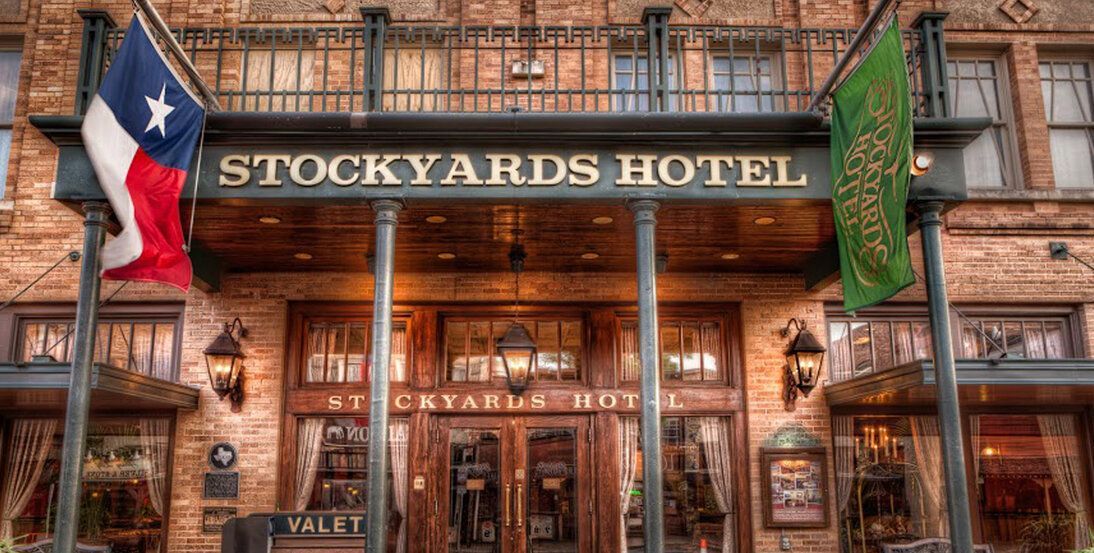 The stockyards hotel is a brick building with a texas flag flying in front of it.