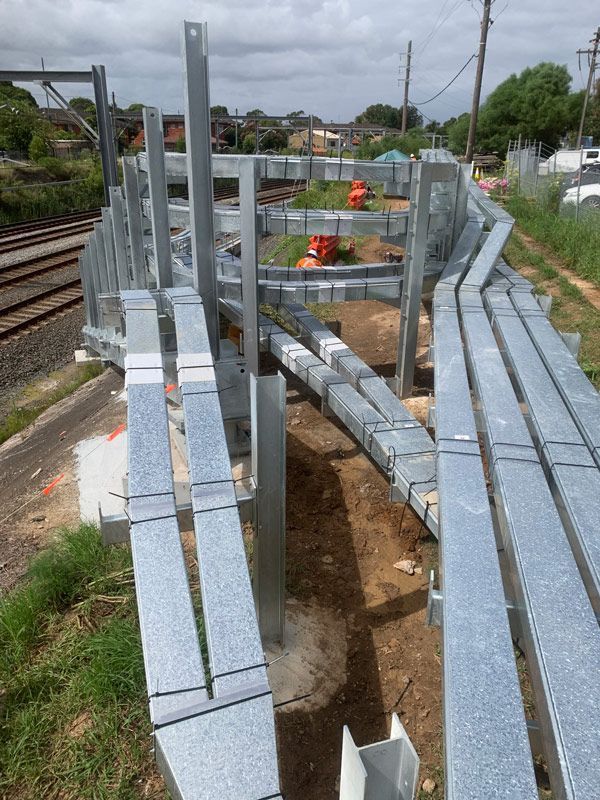 A metal structure is being built next to a train track.