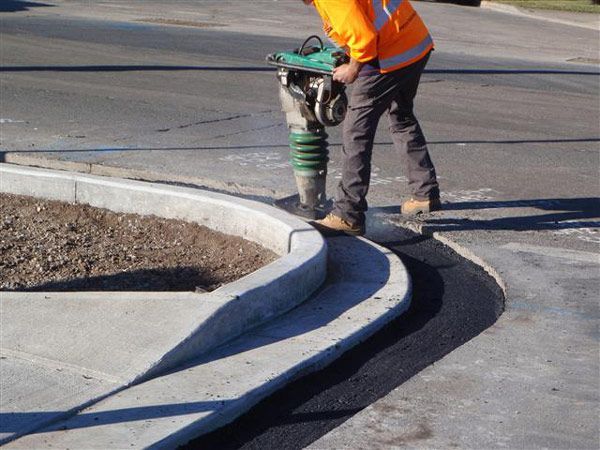 A man is working on a curb with a machine