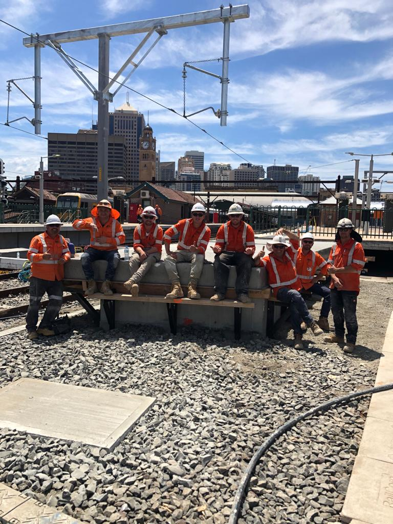 A group of construction workers are sitting on a bench.