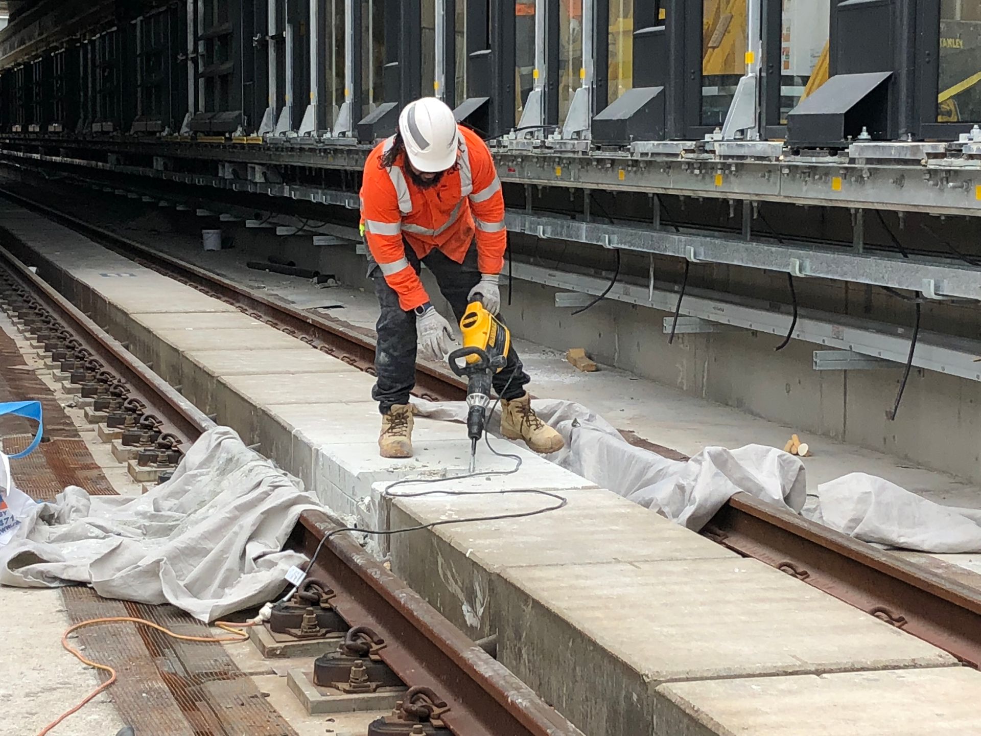 A man is using a drill on a train track.