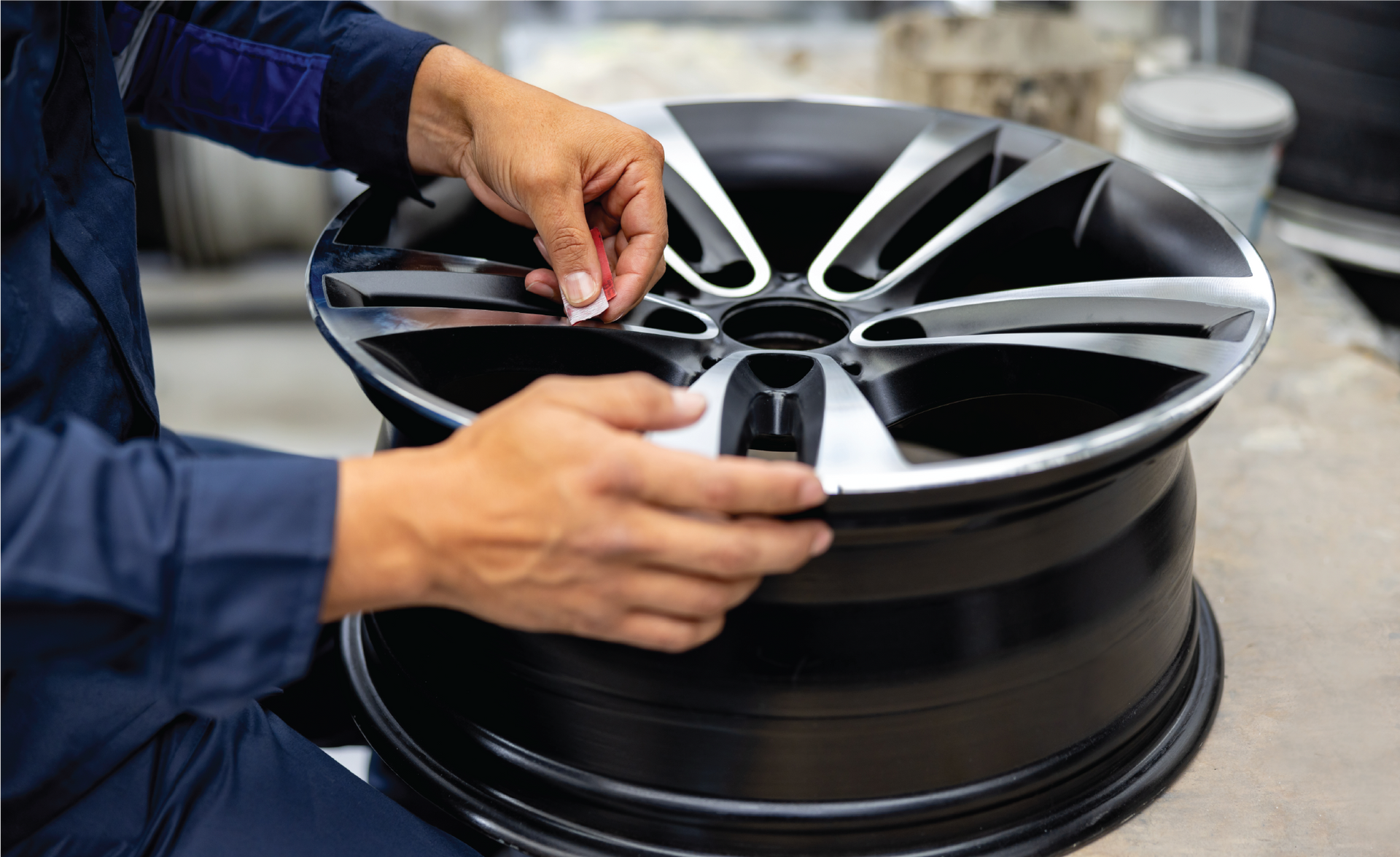 A person is working on a car wheel in a garage.