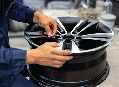 A person is working on a car wheel in a garage.