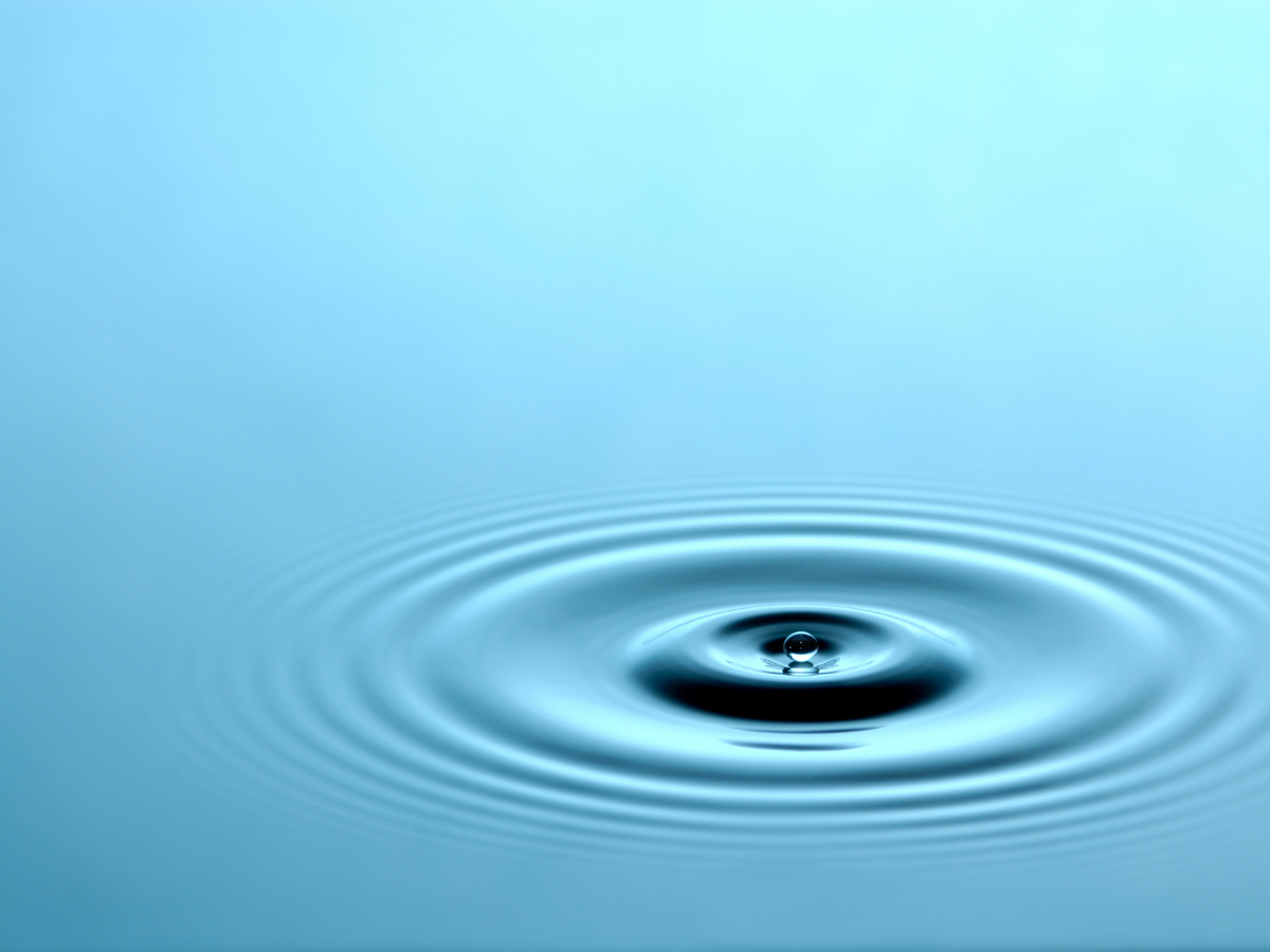 A close up of a drop of water on a blue surface