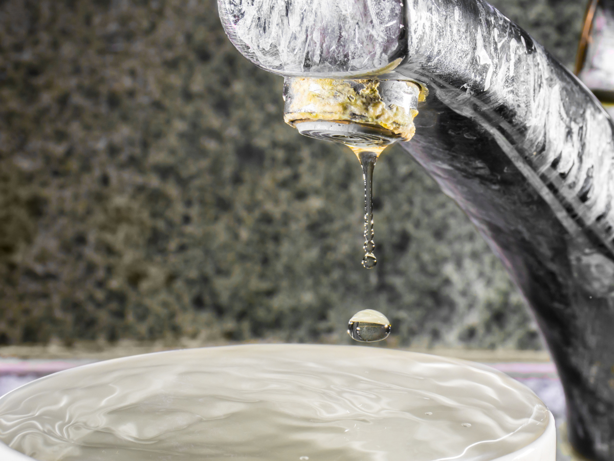A close up of a faucet with water dripping from it.