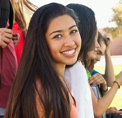 A woman with long hair is smiling in front of a group of people