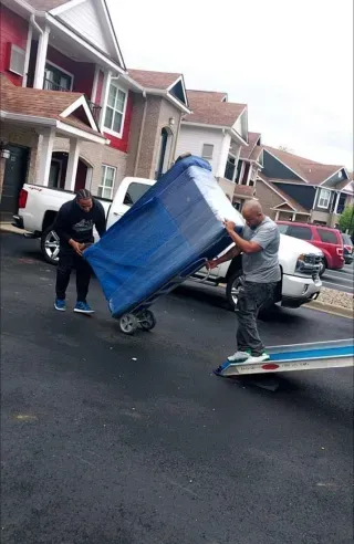 A man is pushing a couch on a dolly down the street.