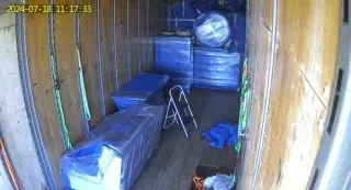 The inside of a moving truck filled with boxes and a ladder.