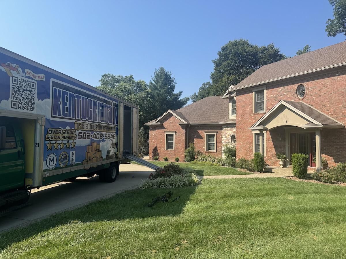 Moving truck parked at a brick house on a sunny day.