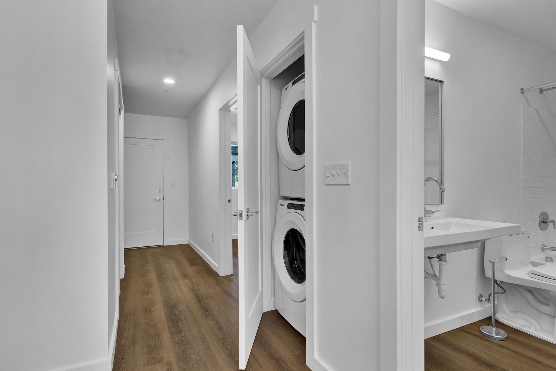 A hallway with a washer and dryer stacked on top of each other.