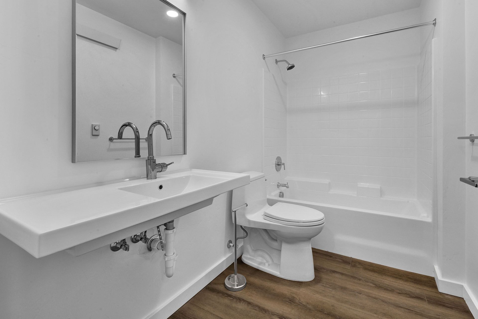 A bathroom with a toilet , sink , tub and mirror.
