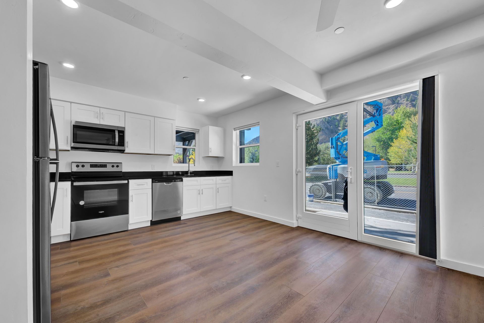 An empty kitchen with stainless steel appliances and hardwood floors.