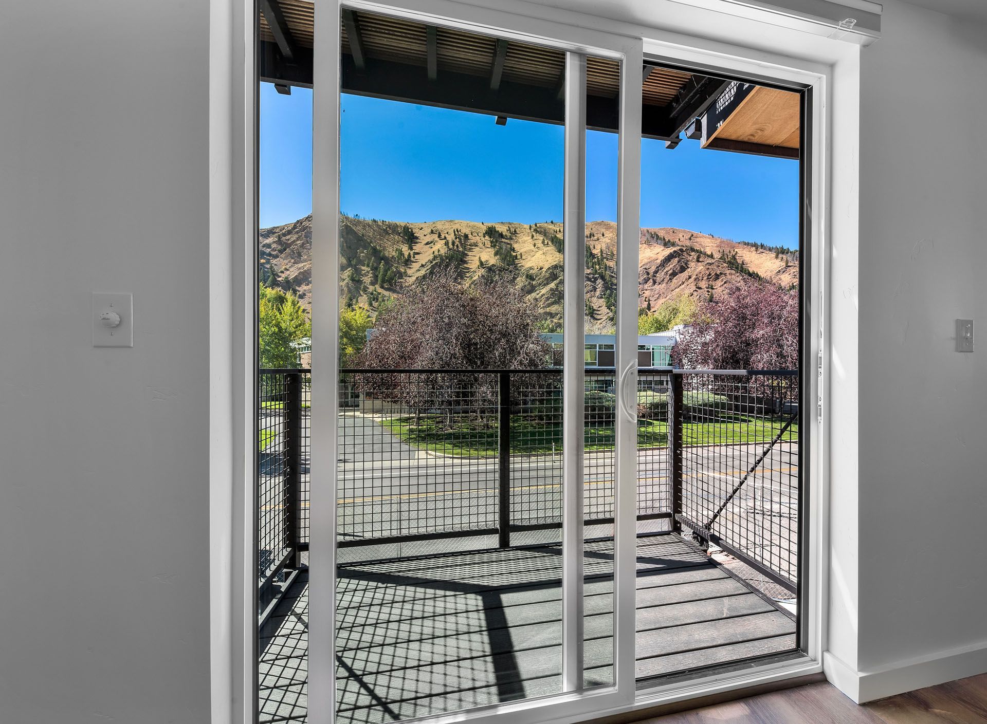 A sliding glass door leading to a balcony with mountains in the background.