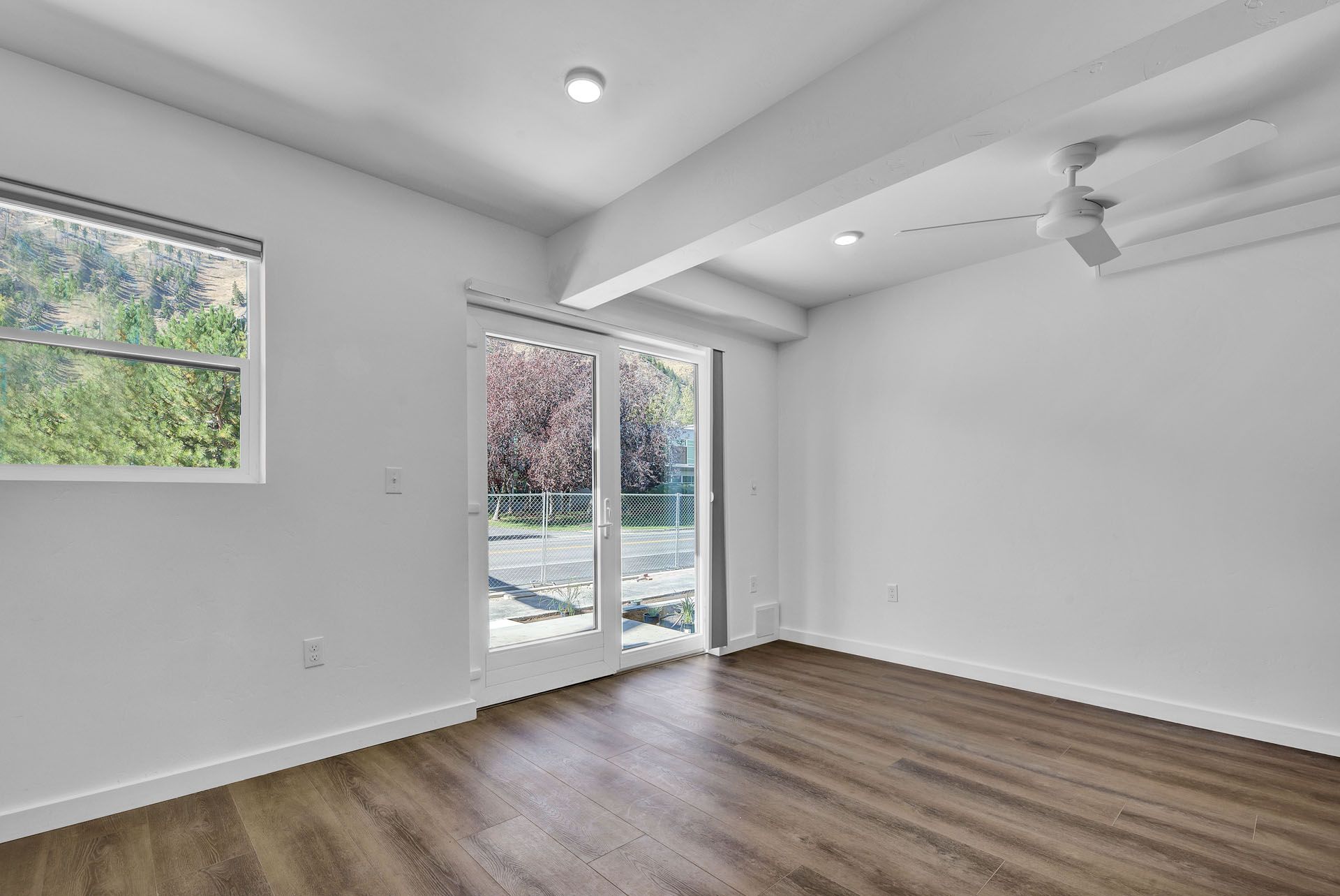 A room with hardwood floors , white walls and sliding glass doors.