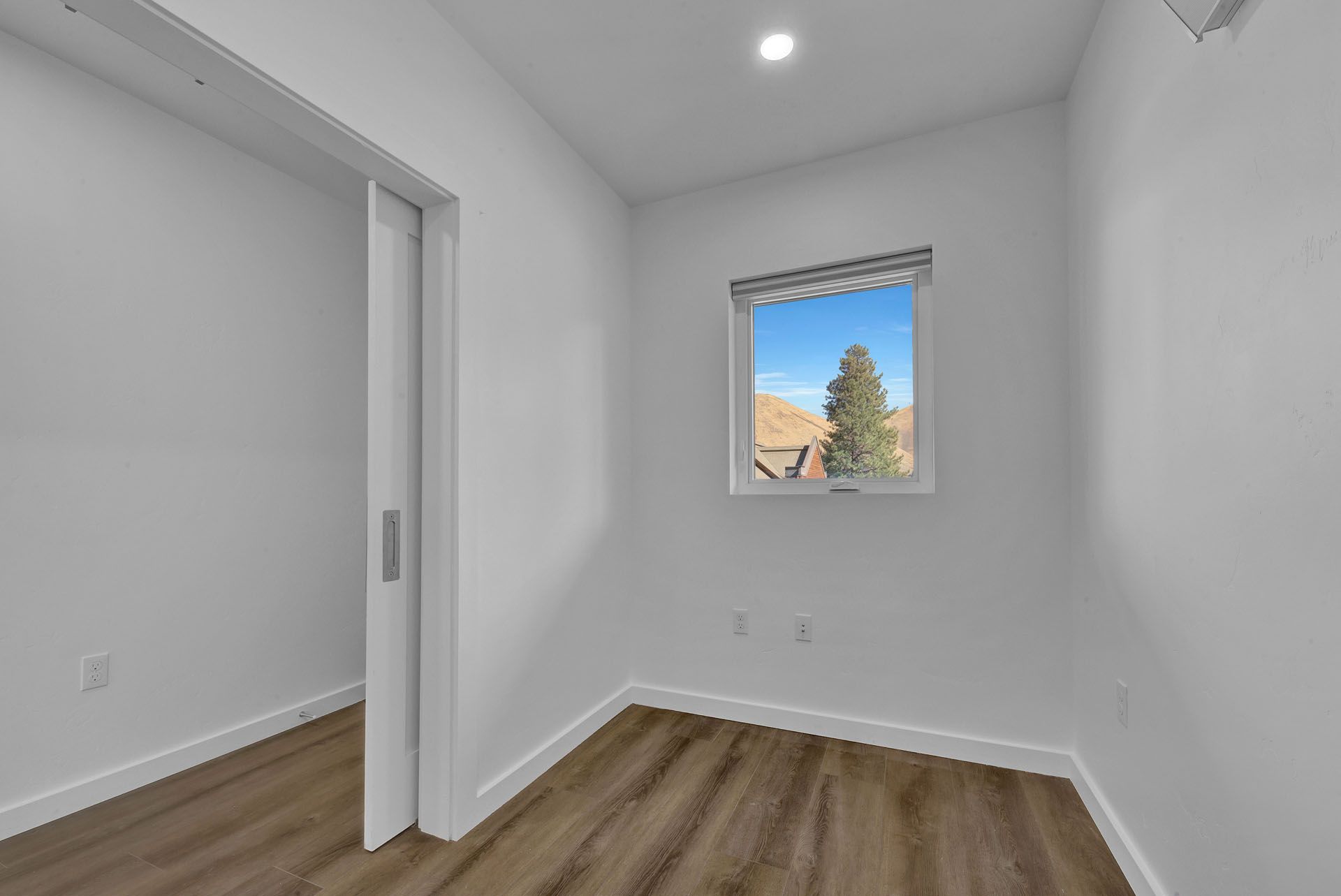 An room with a window and hardwood floors.