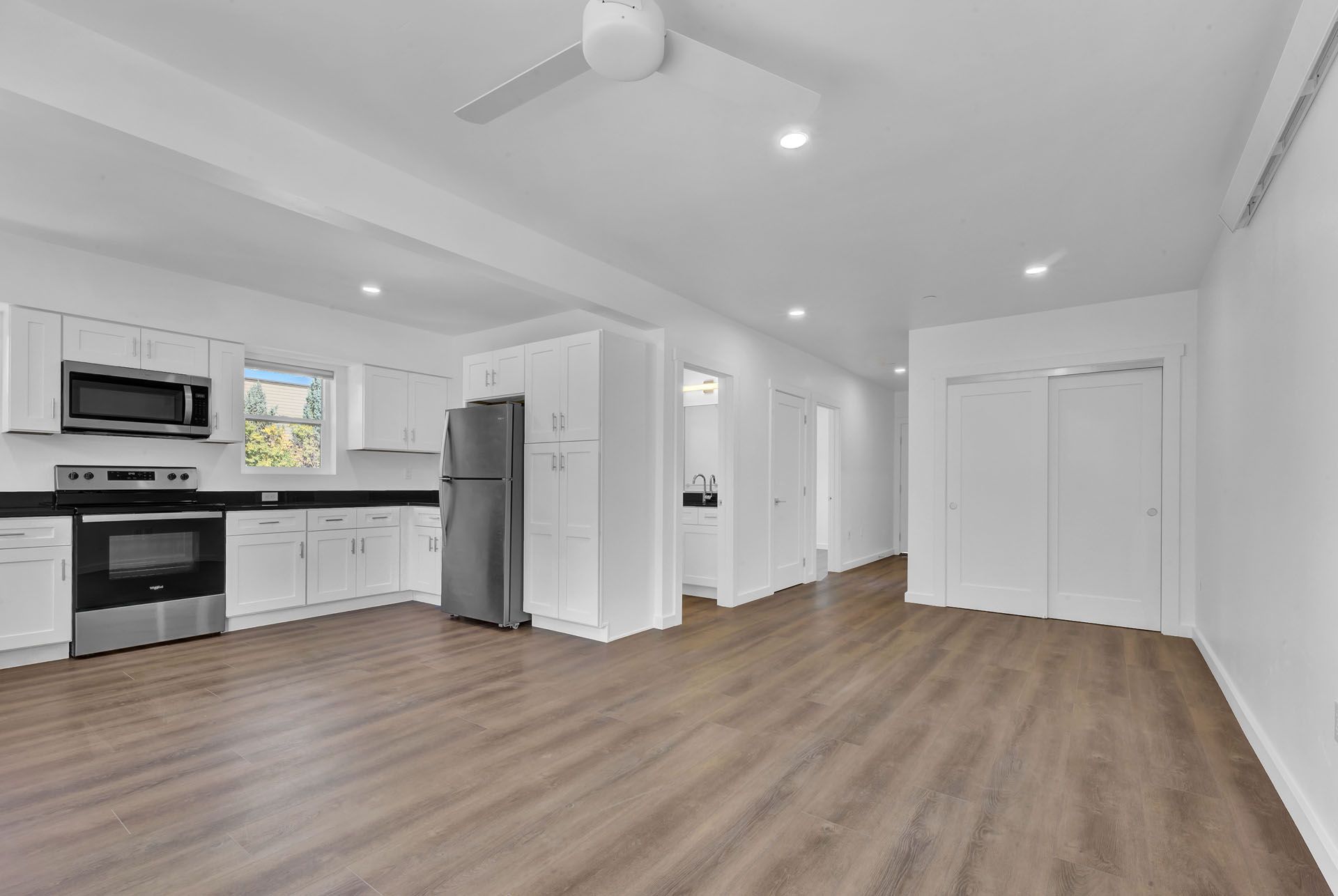 A kitchen with white cabinets , stainless steel appliances , a refrigerator and a microwave.