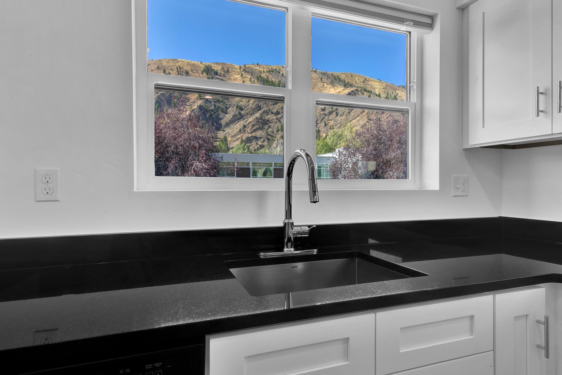 A kitchen with a sink and a window with a view of mountains.