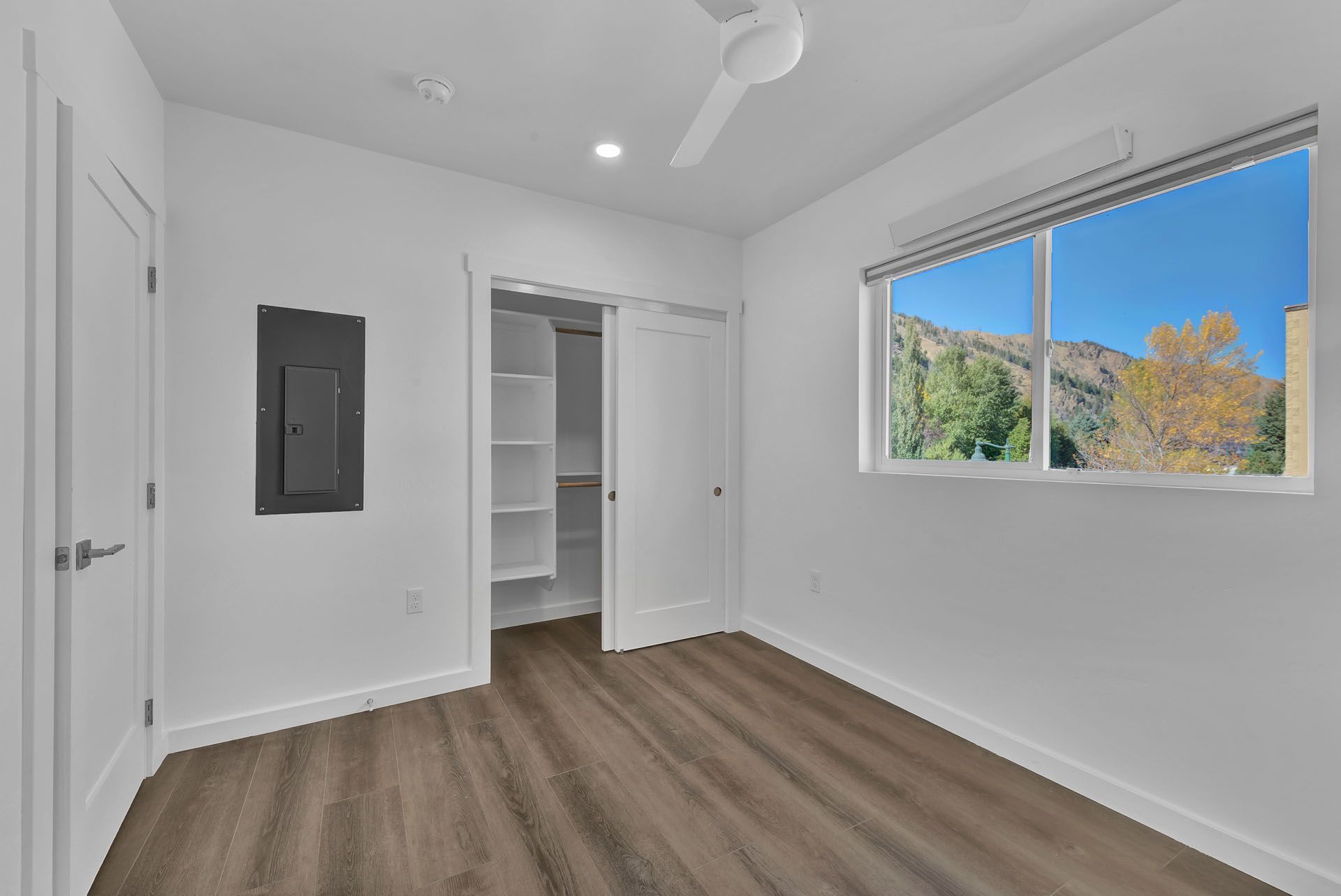 An bedroom with a ceiling fan and a large window.