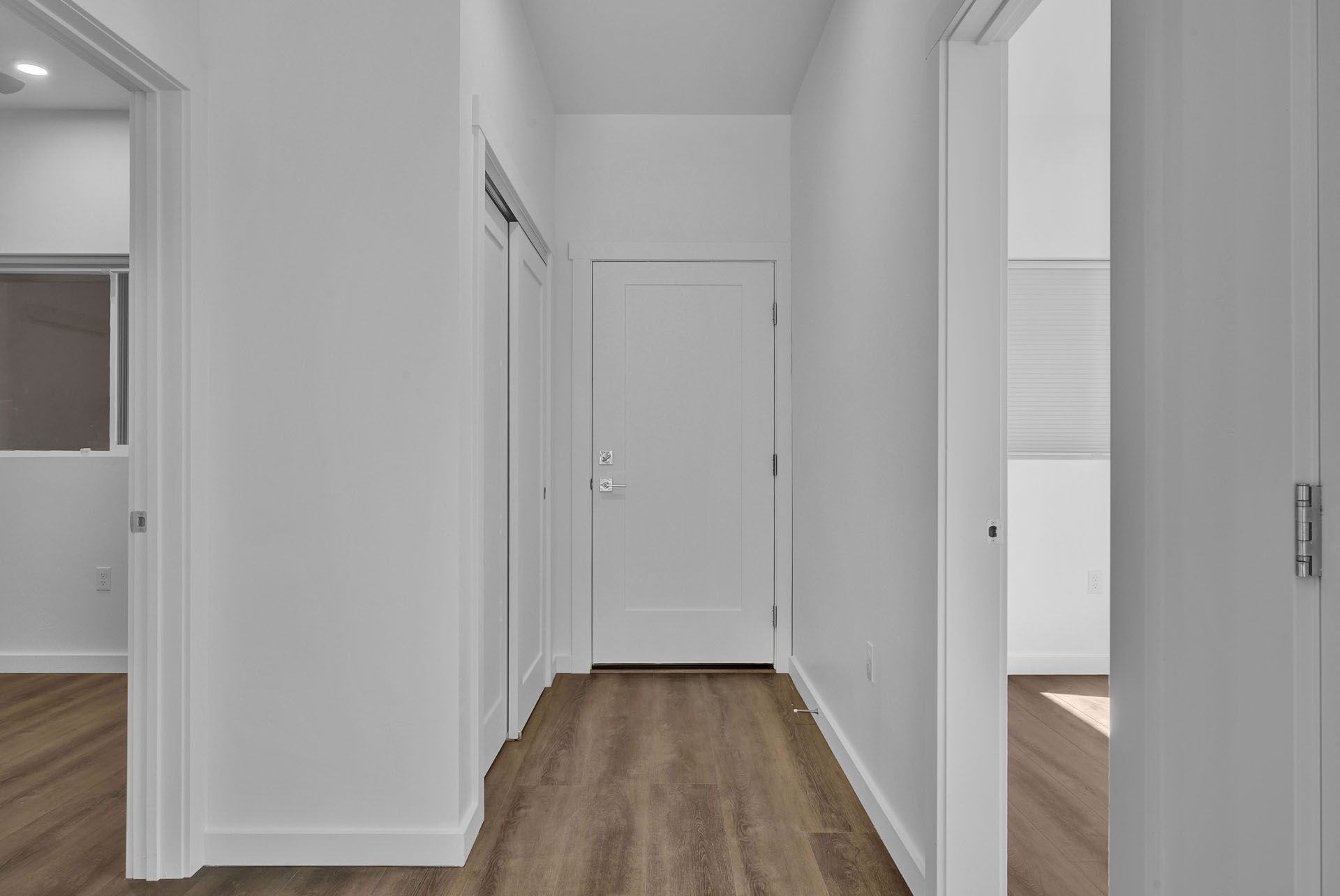 A long hallway with hardwood floors and white walls in a house.