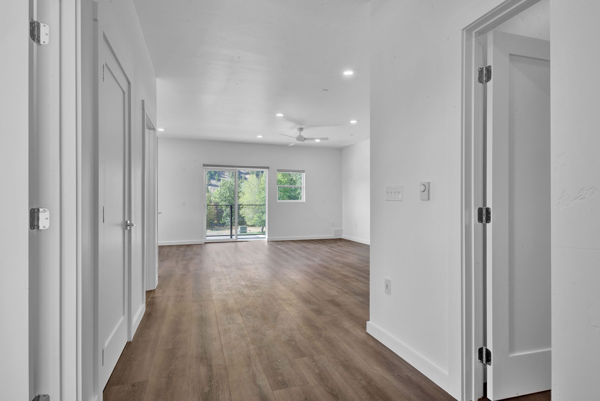A hallway in a house with hardwood floors and white walls.