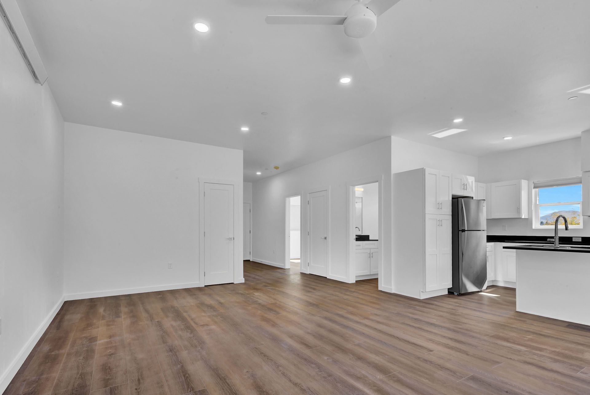 There is a ceiling fan in the living room and a refrigerator in the kitchen.