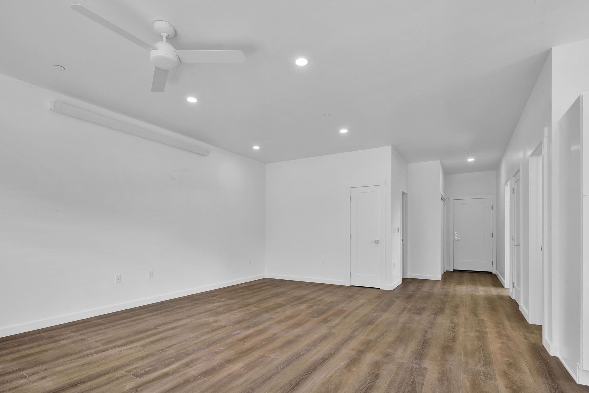 A living room with hardwood floors and a ceiling fan.