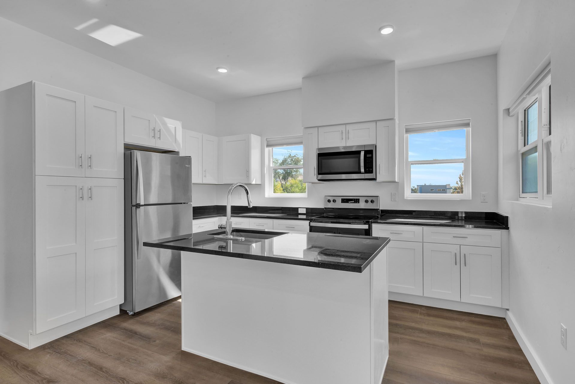 A kitchen with white cabinets , stainless steel appliances , and a large island.