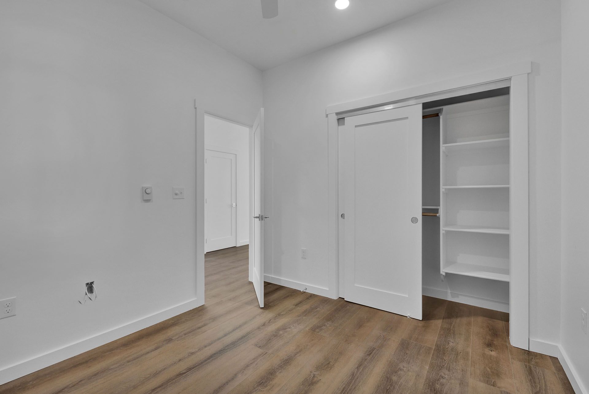 A bedroom with hardwood floors and a closet.