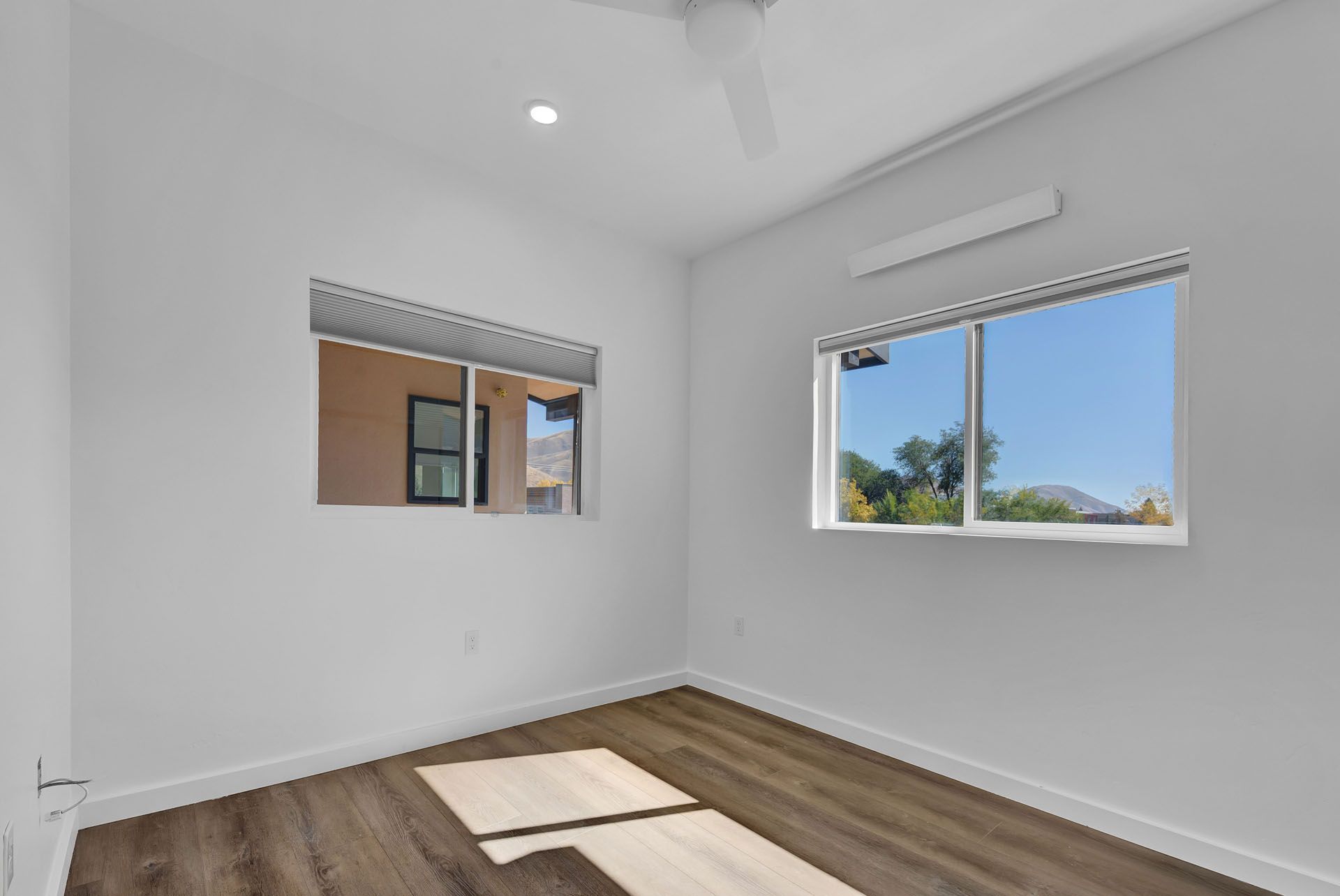 A room with two windows and a ceiling fan.