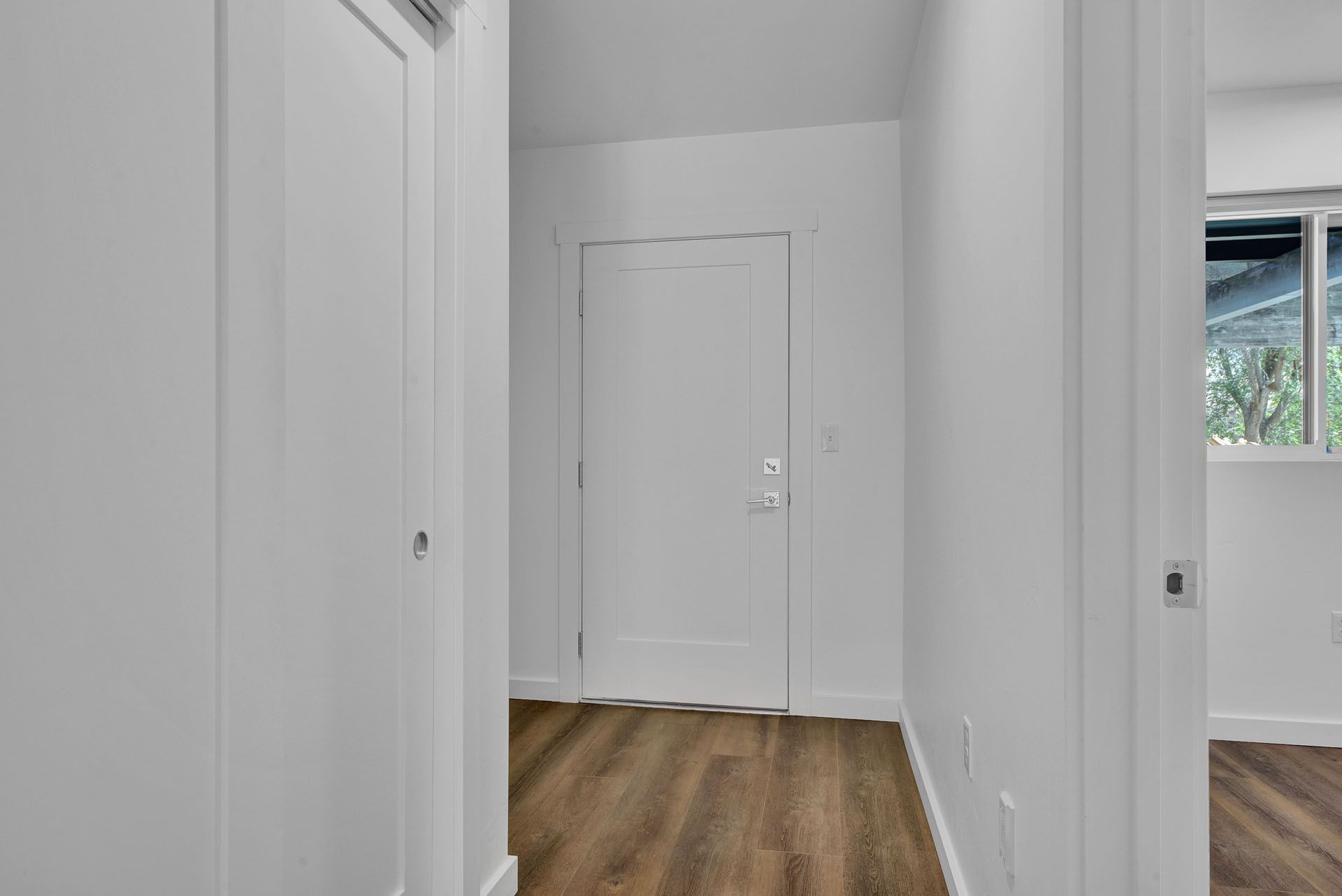 A hallway with hardwood floors and white walls in a house.