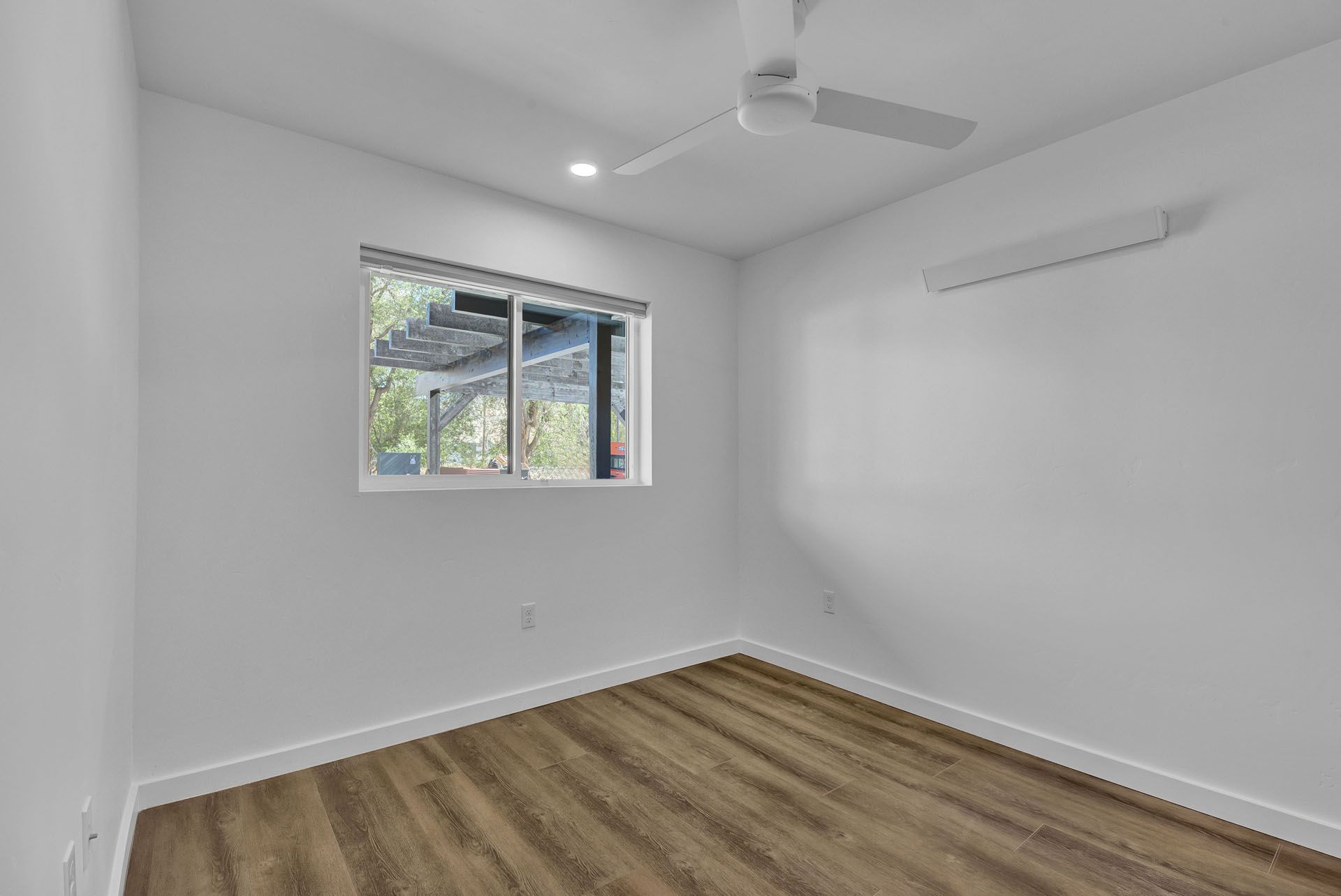 A bedroom with a ceiling fan and a window.