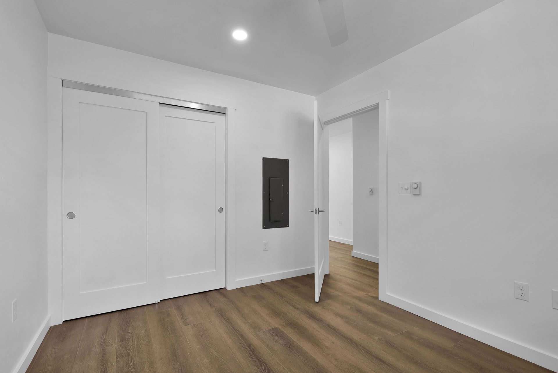 A bedroom with hardwood floors and white walls.