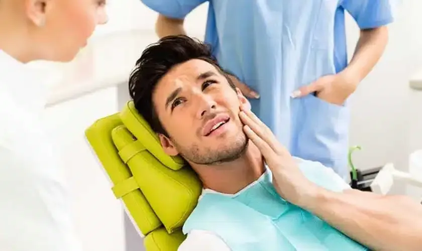 Person clutching jaw in pain — dental emergency relief at Hallmark Dental