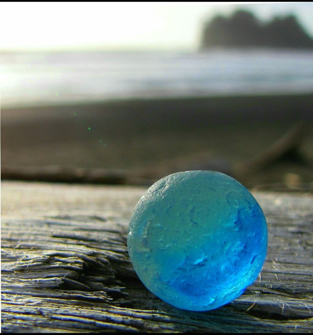 Blue beach glass marble on a log