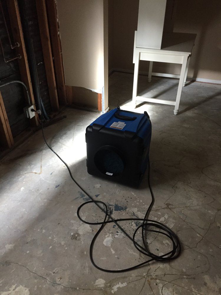 Dehumidifier in a room with exposed framing, power cord on floor.