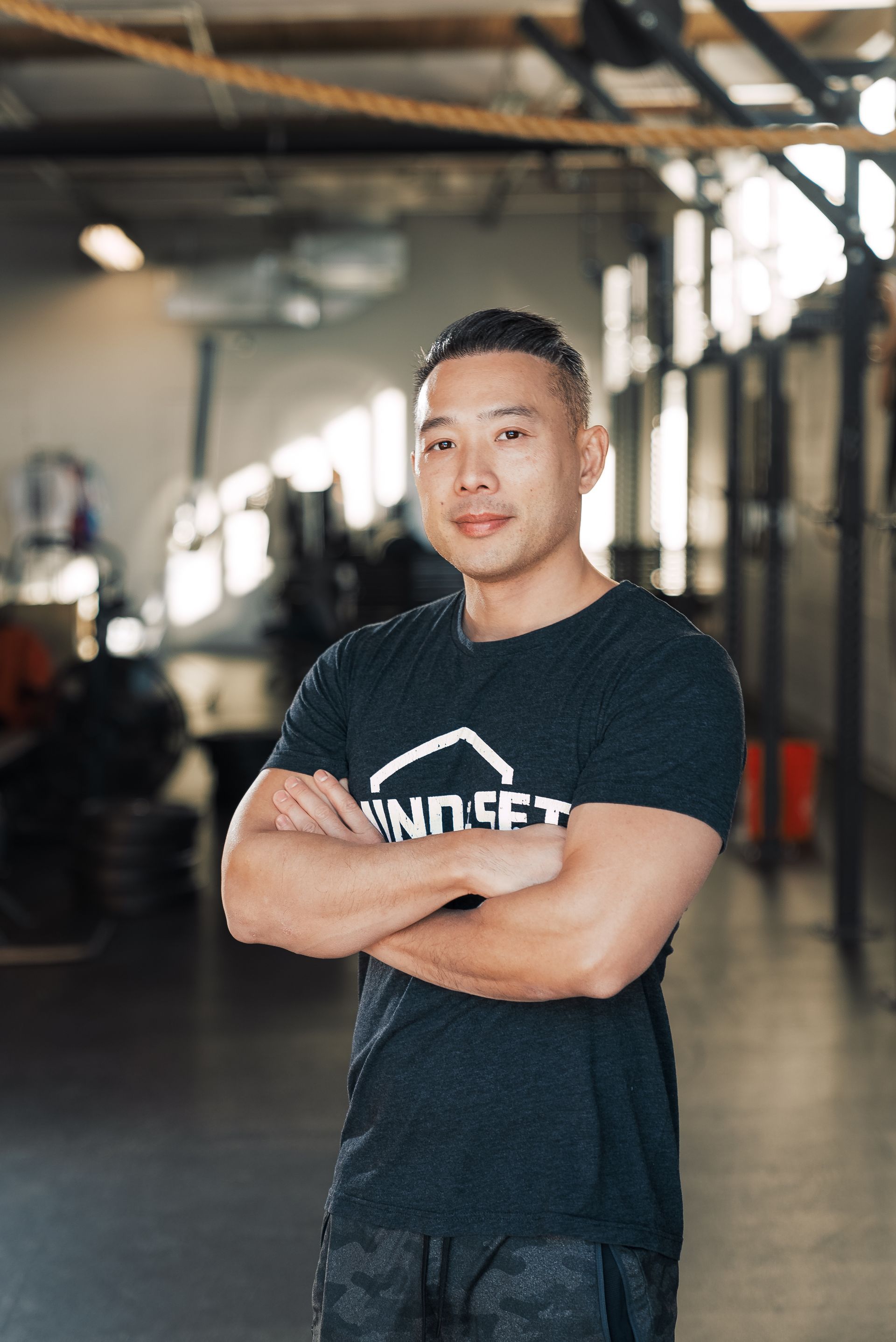 A man is standing in a gym with his arms crossed.