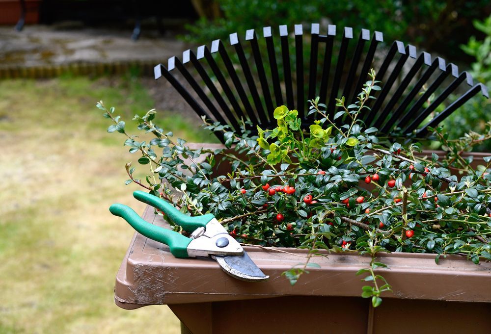A Pair Of Scissors And A Rake Are Sitting In A Garden Planter — Everyday Maintenance Pty Ltd In Beaconsfield, QLD