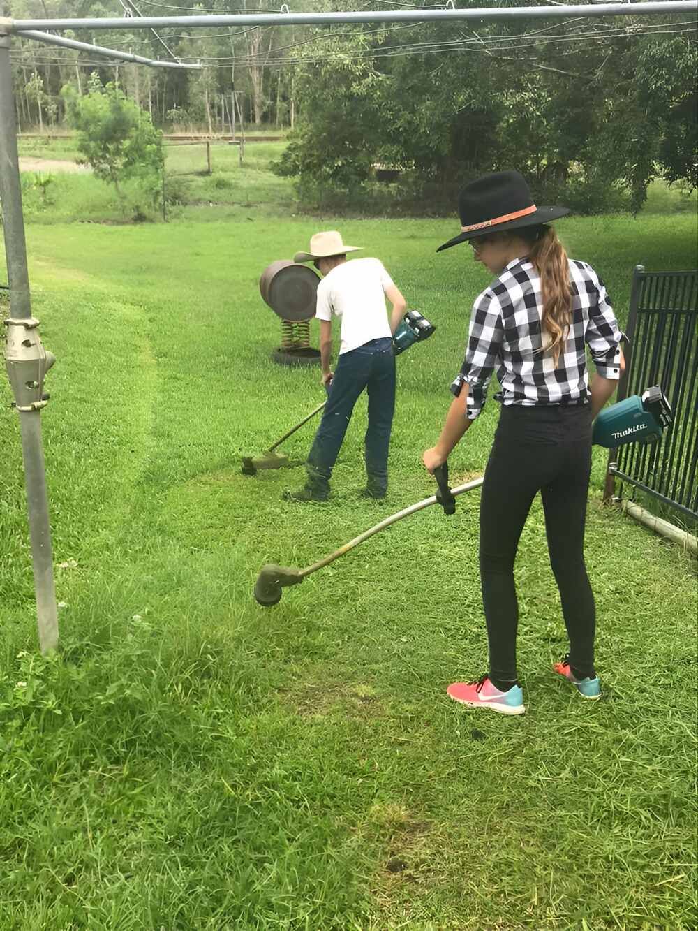 A Man And A Woman Are Mowing The Grass In A Yard — Everyday Maintenance Pty Ltd In Beaconsfield, QLD