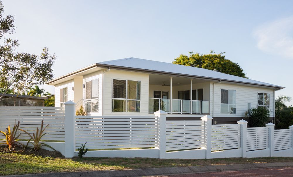 White House With Blue Roof and Front Porch Behind a White Fence — Everyday Maintenance Pty Ltd In Beaconsfield, QLD
