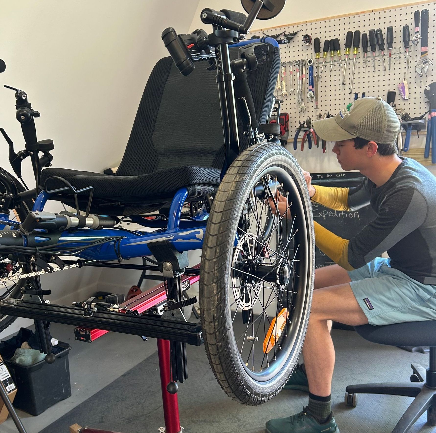 Image shows a young man working on a recumbent trike