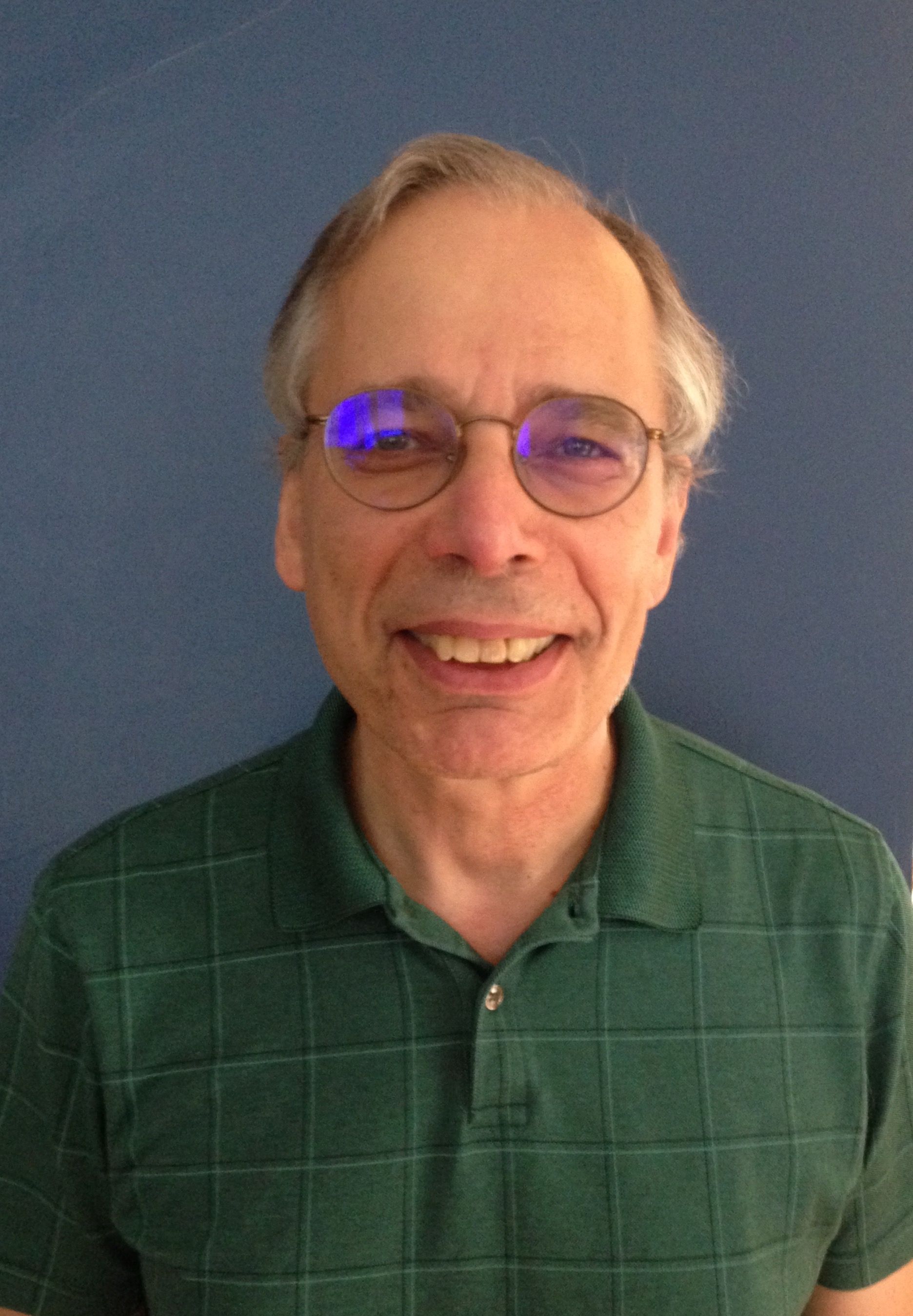 Philippe Galaski, wearing glasses and a green shirt, smiles for the camera